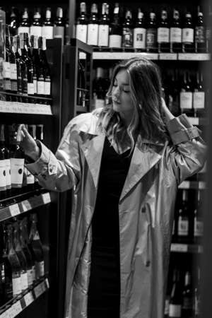 sexy attractive woman in a wine shop among shelves with wine. black and white photo. soft focus.