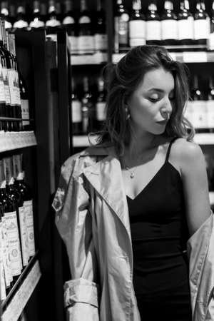 sexy attractive woman in a wine shop among shelves with wine. black and white photo. soft focus.のeditorial素材