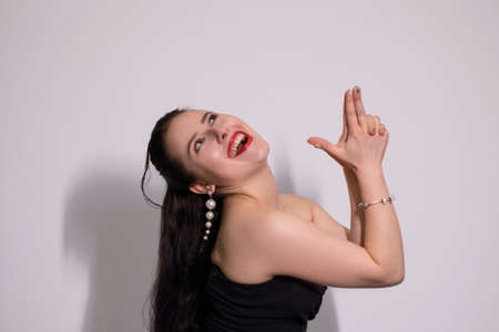 emotional portrait of attractive brunette in black top with white pearl earrings on white...