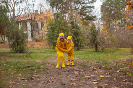 Cute little boy and a girl - brother and sister - in identical yellow costumes and hats walking in the forest. Cosiness, family.の写真素材