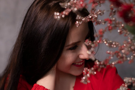 portrait of attractive brunette woman in red blouse near decorative sparkling red branches boquet. copy space. st valentinesの写真素材