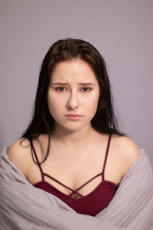charming sleepy brunette girl burst into tears in bed with grey bed linens. morning routine, sadness loneliness, pain. copy spaceの写真素材