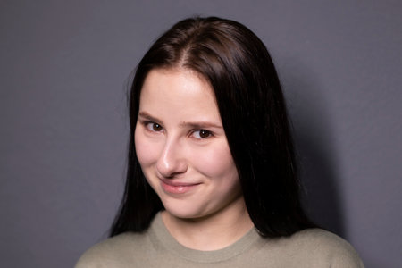 portrait of charming happy brunette woman in marsh color t-shirt on grey wall background. actress...