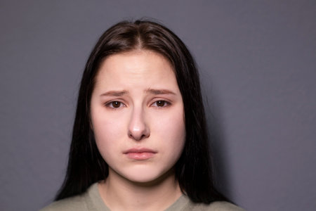 portrait of charming sad brunette woman in marsh color t-shirt on grey wall background. actress acting, emotion. copy spaceの写真素材
