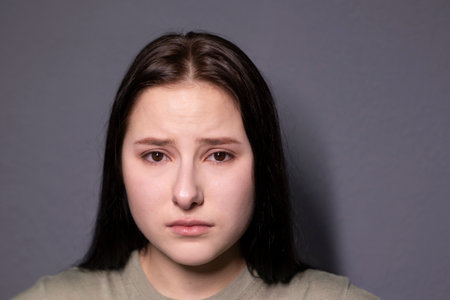 portrait of charming sad brunette woman in marsh color t-shirt on grey wall background. actress acting, emotion. copy spaceの写真素材