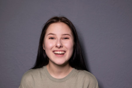 portrait of charming happy brunette woman in marsh color t-shirt on grey wall background. actress acting, emotion. copy spaceの写真素材