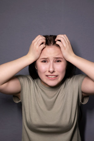 portrait of charming scared brunette woman in marsh color t-shirt on grey wall background. actress acting, emotion. copy spaceの写真素材
