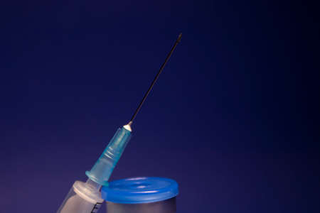Vaccine bottle phial with no label, medical syringe injection needle. isolated on blue background. Development of vaccine . cure. World race in researching. copy spaceの写真素材