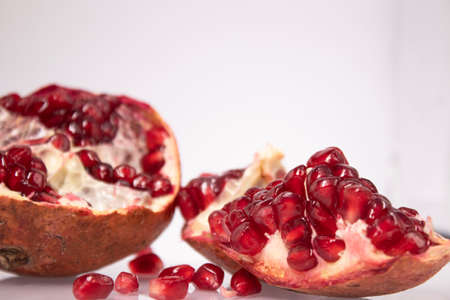 ripe fresh sliced pomegranate fruit with red seeds isolated on white backgroundの写真素材