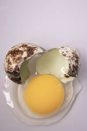 broken Quail egg isolated on white background with leaking white and yolk. healthy raw food.