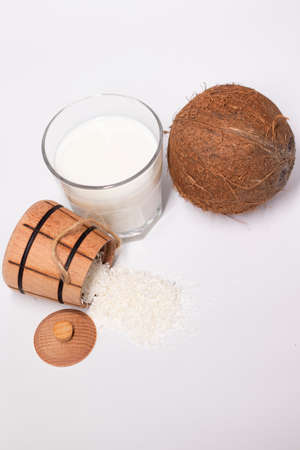 fresh coconut near wooden bowl with coconut flakes and glass of coco milk. isolated on white background. tropical nut.の写真素材
