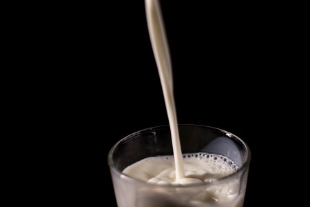 pouring milk in a glass. splash of white liquid isolated on dark background.の写真素材