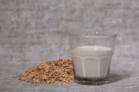 pile of raw oatmeal near a glass of milk. healthy breakfast. vegan oat milkの写真素材