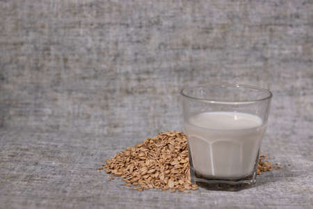 pile of raw oatmeal near a glass of milk. healthy breakfast. vegan oat milkの写真素材