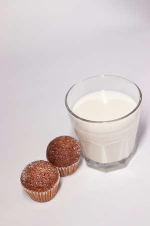 two little cupcakes or muffins in powdered sugar near a glass of milk. healthy breakfast. snack or lunch.の写真素材