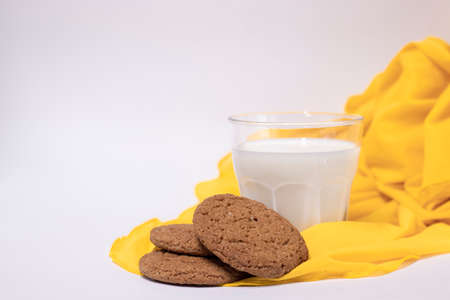 oat cookies with a glass of milk on yellow silk fabric isolated on white background.の写真素材