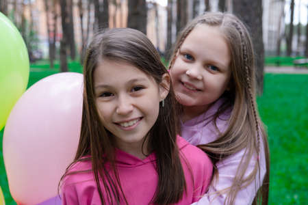two pretty teenage girls friends with colorful balloons in park. happy kids. summer days. vacation,...
