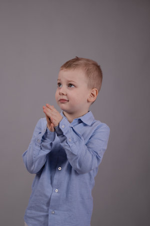 charming little preschool boy in white pants and blue shirt on gray background. child, kid.の写真素材