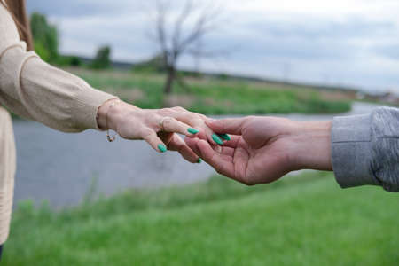 Hands of man and woman reaching to each other. Soft, gentle touch of hands on background of nature. Be hand in hand. Concept of Love, connection, help, relation, community, togetherness, symbolism.の写真素材