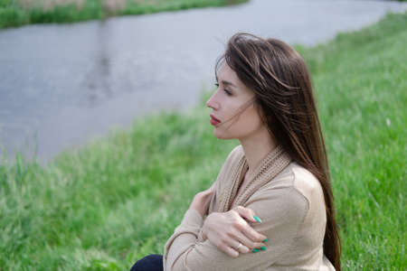 beautiful brunette woman sitting on green grass.の写真素材
