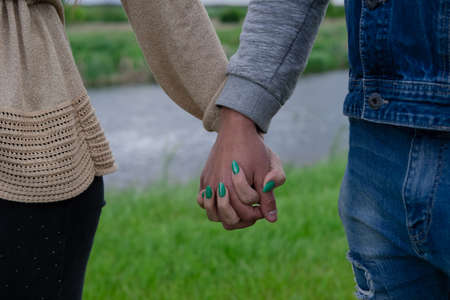 hands of man and woman touch on the background of nature.の写真素材