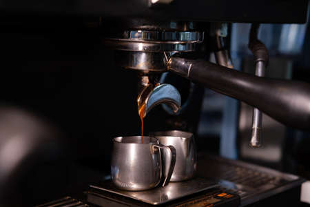 black coffee is pouring from professional coffee machine. coffee making by barista. dark loft coffee shop.の写真素材
