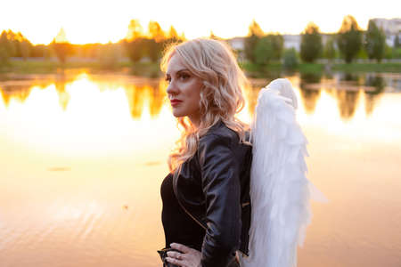 dark angel. blonde sexy woman in black leather clothes with white angels wings.の写真素材