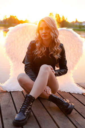 dark angel. blonde sexy woman in black leather clothes with white angels wings.の写真素材