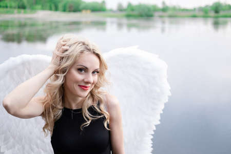 portrait of a sensitive woman with white angel wings. wearing black leather clothes. fallen dark angel. demon. beastの写真素材