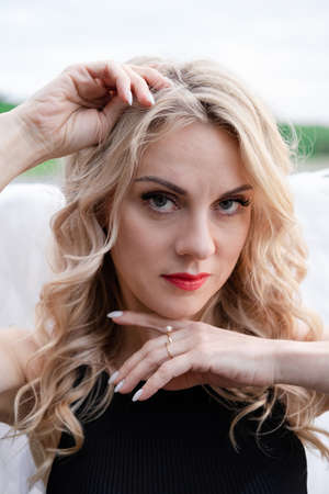 portrait of a sensitive woman with white angel wings. wearing black leather clothes. fallen dark angel. demon. beastの写真素材