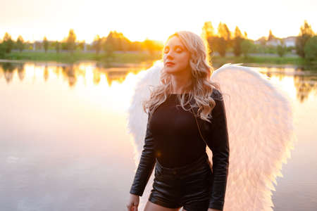 woman with white angel wings. wearing black leather clothes. fallen dark angel. demon. beast. girl in angel costumeの写真素材