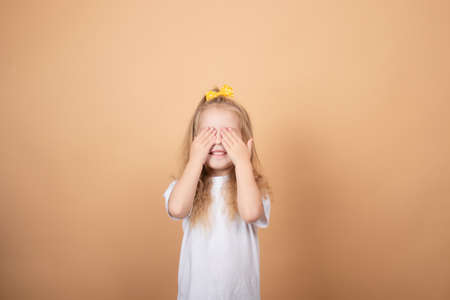 adorable blonde little girl in white t-shirt. on brown - yellow background. innocence child portrait.の写真素材