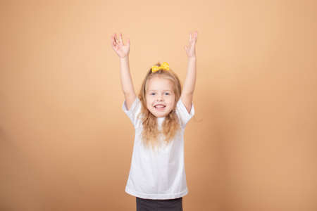 adorable blonde little girl in white t-shirt. on brown - yellow background. innocence child portrait.の写真素材