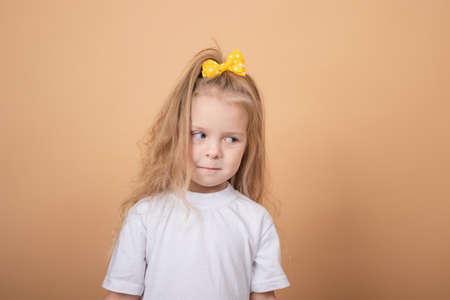 adorable blonde little girl in white t-shirt. on brown - yellow background. innocence child portrait.の写真素材