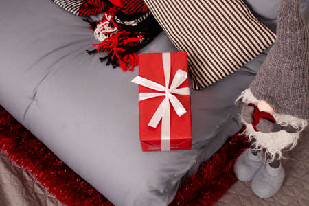 cozy christmas photo zone. gray sofa with red checkered blanket. red garland on white brick wall. red gift box and toy santa claus.の写真素材
