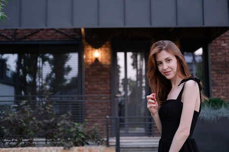 single confident woman near her new home. brown and black modern building. happy care free suburb life.の写真素材