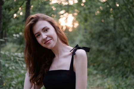 attractive young brunette woman in a black dress posing in the forest. freedom. fashion portrait.の写真素材
