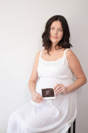 pregnant woman with a photo of ultrasound of pregnancy. enjoying pregnancy happy time. mother to be with cute big tummy.の写真素材