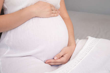 expecting mother with huge tummy. sweet pregnancy time. happy woman with pregnant belly in light bedroom. home cozy interiorの写真素材