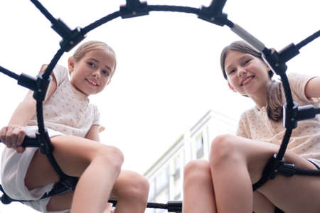 two pretty teen girls playing on a modern playground in identical clothes. sister, bffs. sisterhood,...