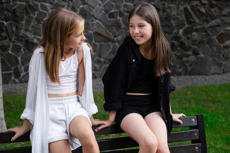 fraternal twin sisters. blonde and brunette teen girls in fashionable black and white clothes...