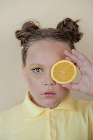 charming tween girl with slices of ripe lemon on yellow background. juicy fruit concept. summer.の写真素材