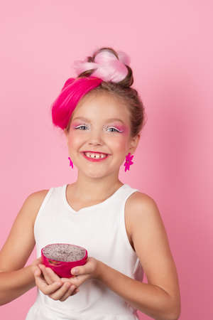 sweet Girl is holding a Pitahaya near her face. A pitaya fruit hold in hand on pink background. Tropical Dragon Fruit cut in half. space for textの写真素材