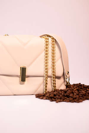 fashion beige leather woman handbag with gold chain with coffee beans nearby isolated on white background. product photography. bags and purses for women.の写真素材
