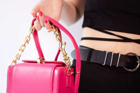 woman's hand holding a pretty little pink handbag. product photography. stylish handbag and purse for womenの写真素材