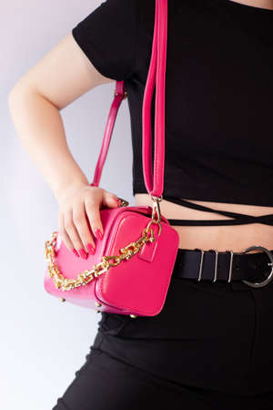 woman's hand holding a pretty little pink handbag. product photography. stylish handbag and purse for womenの写真素材