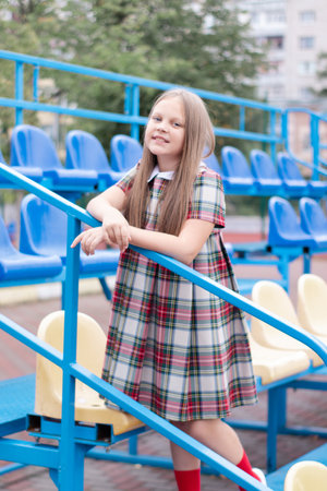 stadium tribunes. tweet brunette girl in dress near Tribunes and plastic colorful chairs in the sports stadiumの写真素材
