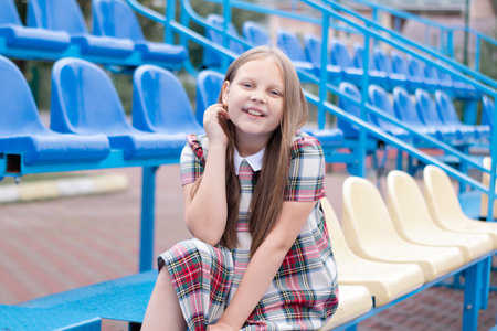 stadium tribunes. tweet brunette girl in dress near Tribunes and plastic colorful chairs in the sports stadiumの写真素材