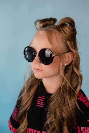 fashion teenager portrait. tween school girl with orange makeup wearing pink stylish cool clothes on blue background.の写真素材