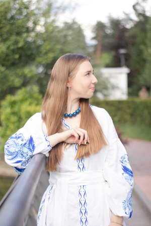 ukrainian blonde girl in national blue dress - embroidered shirt. young woman patriot. outdoors photo of charming female.の写真素材